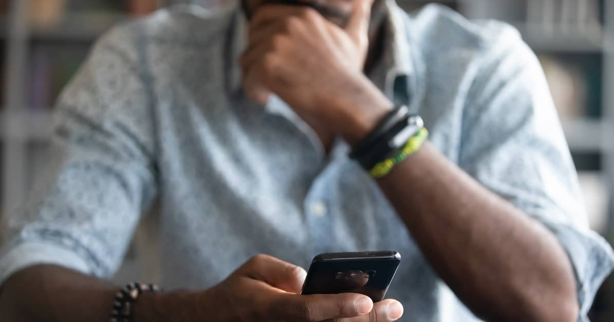 man looking at phone and wondering, "Should I call a foster care abuse lawyer?"